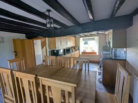 A kitchen with wooden dining table and chairs wooden cabinets and a window with a view at Gwrtheyrn in Dyffryn Ardudwy