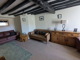 A living room with two sofas wooden side tables a wooden cabinet and a lamp at Gwrtheyrn in Dyffryn Ardudwy
