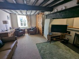 A living room with leather chairs a wooden cabinet a television and a green rug at Gwrtheyrn in Dyffryn Ardudwy