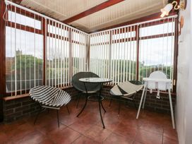 A conservatory with chairs and a table at Eryl in Nefyn