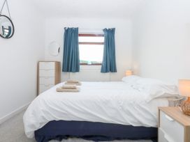 A bedroom with a bed and dresser at Eryl in Nefyn