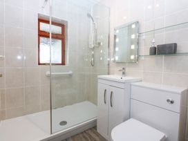 A bathroom with a shower, toilet, sink, and mirror at Eryl Nefyn
