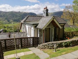 Exterior view of a small house with a stone wall and garden in a rural setting with hills in the background at The Nook in Maenan