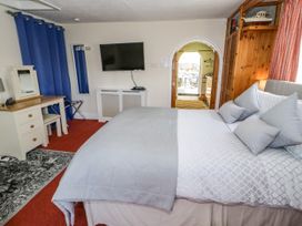 A bedroom with a bed pillows TV desk mirror and an arched doorway at The Nook in Maenan