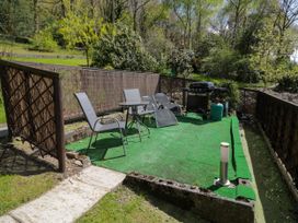A small outdoor patio with metal chairs and table and a barbecue grill surrounded by wooden fencing at The Nook in Maenan