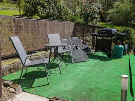 An outdoor patio with chairs a small round table a barbecue grill and a green artificial grass surface at The Nook in Maenan