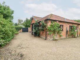 A house with rose bushes near a gravel driveway at Lowbrook Cottage Dickleburgh near Diss