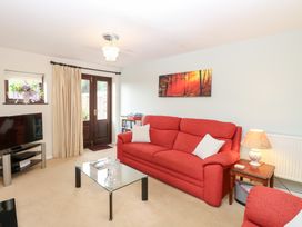 A living room with a television and a red sofa at Lowbrook Cottage Dickleburgh near Diss
