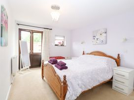 A bedroom with a wooden bed and a mirror at Lowbrook Cottage Dickleburgh near Diss