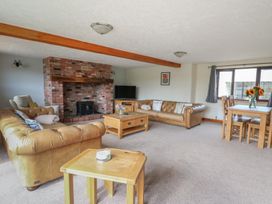 A living room with a fireplace and a dining table at Glanyrafon in St Harmon