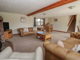A living room with a sofa, coffee table, and dining area at Glanyrafon in St Harmon