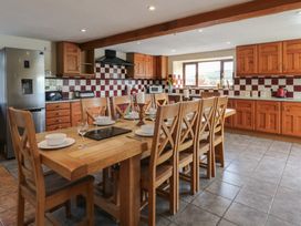 A kitchen with wooden table and chairs at Glanyrafon in St Harmon