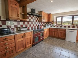 A kitchen with wooden cabinets and appliances at Glanyrafon in St Harmon