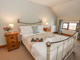 A bedroom with a bed, bedside table, and window at Glanyrafon St Harmon