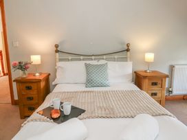 A bedroom featuring a bed with pillows and a bedside table at Glanyrafon in St Harmon