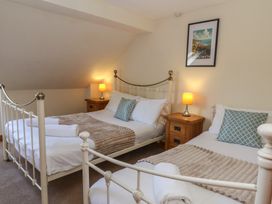 Two beds with a nightstand and lamp in a bedroom at Glanyrafon St Harmon