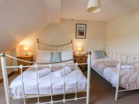 A bedroom with two beds and bedside table at Glanyrafon St Harmon