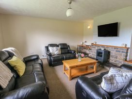 A living room with a sofa, coffee table, and television at Glanyrafon Bungalow in St Harmon