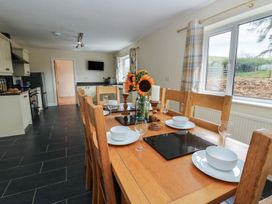 A kitchen with a dining table set up at Glanyrafon Bungalow St Harmon
