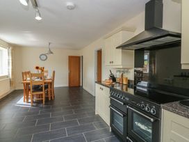 A kitchen with a dining table and chairs at Glanyrafon Bungalow St Harmon