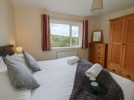 A bedroom with a bed and window at Glanyrafon Bungalow in St Harmon