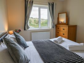 A bedroom with a bed and window view at Glanyrafon Bungalow, St Harmon
