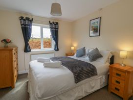 A bedroom with a double bed and window at Glanyrafon Bungalow in St Harmon