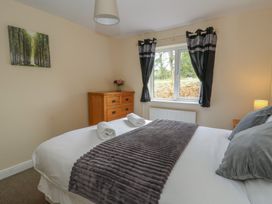 A bedroom with a bed and window at Glanyrafon Bungalow St Harmon