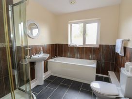 A bathroom with shower, bathtub, sink, and toilet at Glanyrafon Bungalow St Harmon