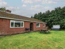 A bungalow with a picnic table and hot tub at Glanyrafon Bungalow in St Harmon