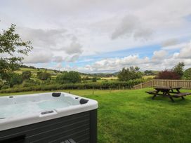 A hot tub and picnic table in a garden at Glanyrafon Bungalow St Harmon