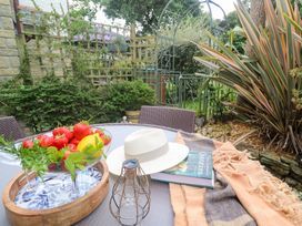A garden table with fruit, a hat, a book and a blanket at Tranquility in Falmouth