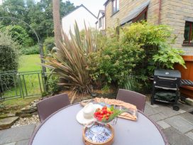 An outdoor area with a table, plants, and a barbecue at Tranquility in Falmouth