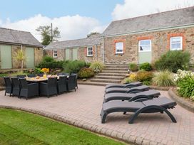 An outdoor area with table and chairs next to sun loungers at Silvermine House Charlestown