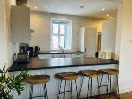 A kitchen with bar stools and appliances at Trearddur View in Treaddur Bay
