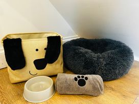 A dog bed, storage basket, bowl and towel at Trearddur View in Treaddur Bay