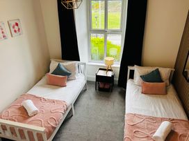 A bedroom with two beds, a lamp, and a window at Trearddur View in Treaddur Bay