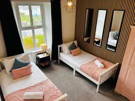 A bedroom with two single beds and a nightstand at Trearddur View in Treaddur Bay