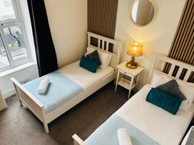 A bedroom with two single beds and a nightstand at Trearddur View in Treaddur Bay