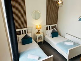 A bedroom with two beds and a lamp on a nightstand at Trearddur View, Treaddur Bay