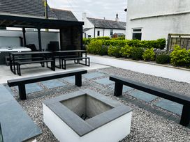 An outdoor area with a hot tub, seating and a fire pit at Trearddur View in Treaddur Bay