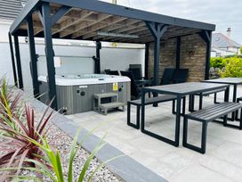 An outdoor area with a hot tub and wooden furniture at Trearddur View in Treaddur Bay