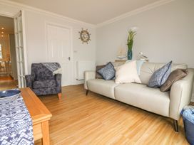 A living room with a beige sofa and cushions a blue armchair a wooden table with a blue patterned runner and nautical decorations at 7 The Retreat in Paignton