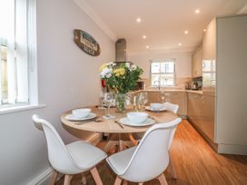 A kitchen with a round dining table set with plates bowls and glasses and a vase with flowers at 7 The Retreat in Paignton
