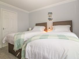 A bedroom with two single beds with headboards and blankets at 7 The Retreat in Paignton
