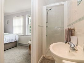 A bathroom with a shower and sink next to a bedroom with a bed and windows at 7 The Retreat in Paignton