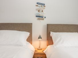 A bedroom with two beds white pillows a wooden nightstand and a lamp at 7 The Retreat in Paignton