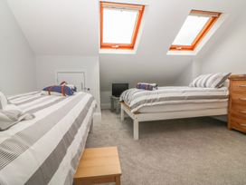 A bedroom with two single beds a wooden nightstand a small table and two skylight windows at 7 The Retreat in Paignton