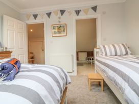 A bedroom with two single beds striped bedding and a small wooden stool at 7 The Retreat in Paignton