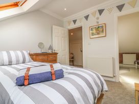 A bedroom with a striped bedspread a wooden chest of drawers and bunting on the wall at 7 The Retreat in Paignton